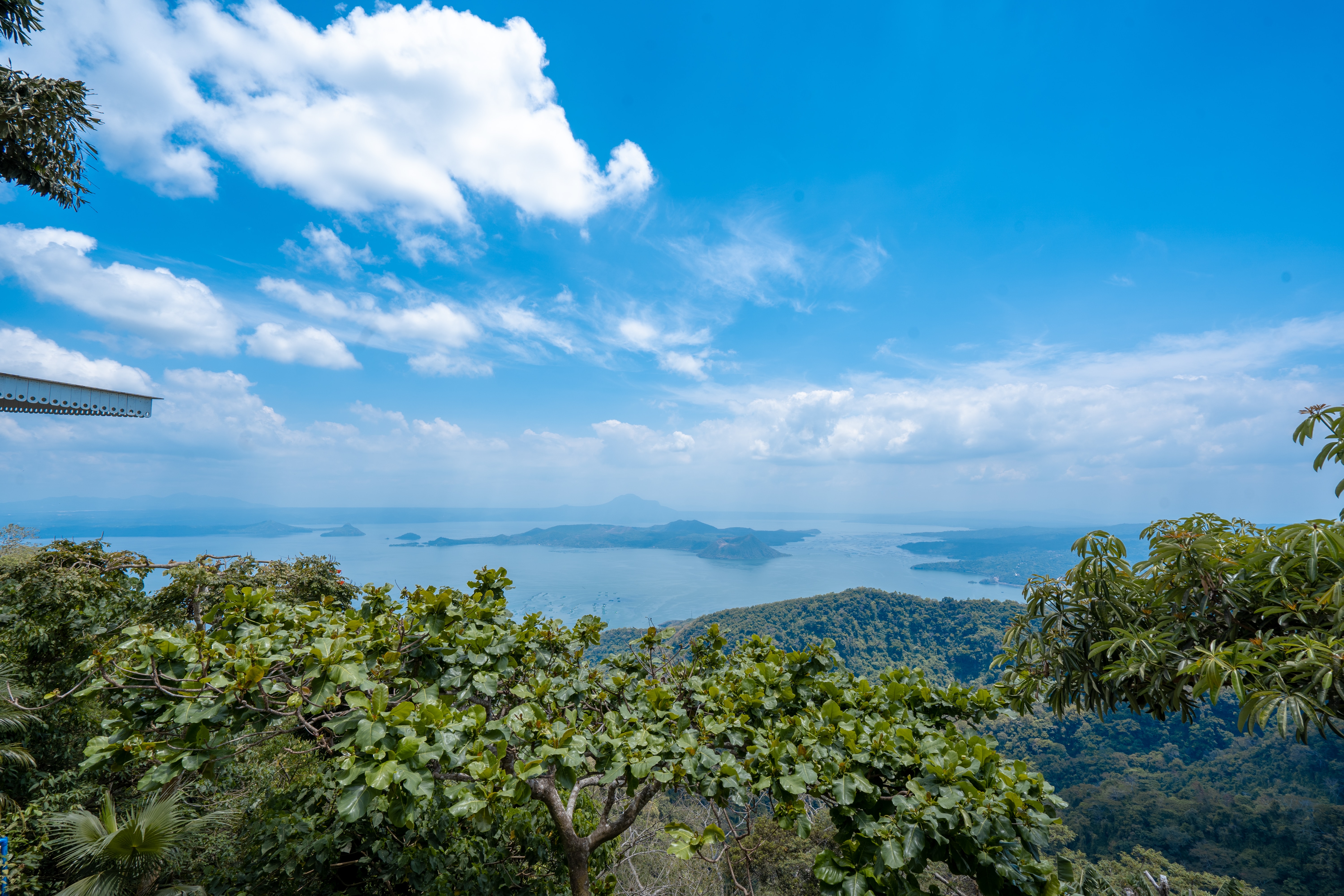 green trees near body of water under blue sky during daytime - condo in tagaytay city by one tolentino east residences taal dc taaldc